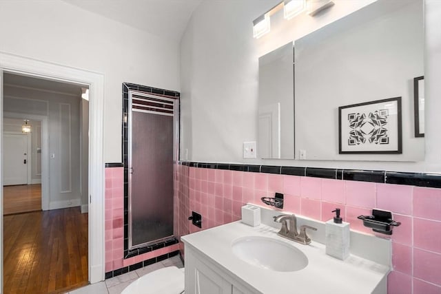 bathroom with hardwood / wood-style floors, a shower, tile walls, vanity, and toilet