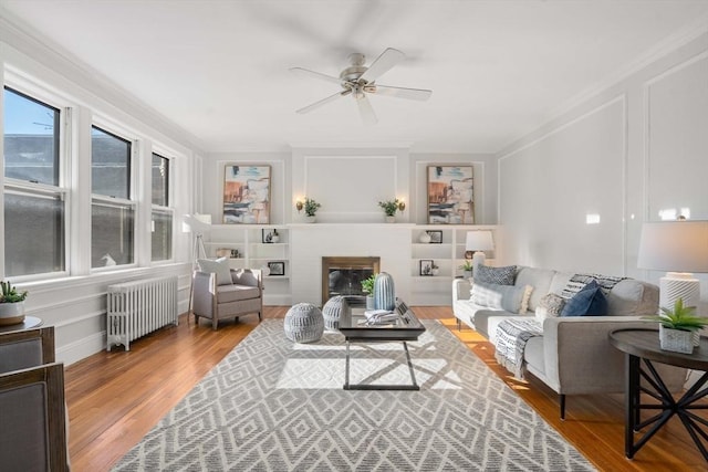 living room featuring hardwood / wood-style floors, radiator heating unit, ornamental molding, and ceiling fan