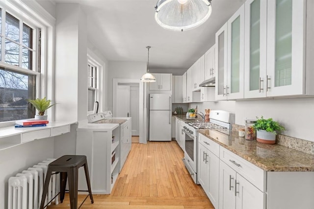 kitchen featuring radiator, white appliances, white cabinetry, hanging light fixtures, and washer / clothes dryer