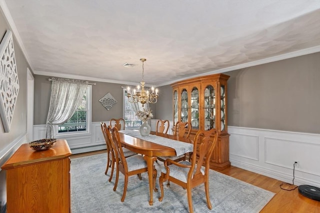 dining room with visible vents, wood finished floors, a wainscoted wall, a baseboard heating unit, and a chandelier