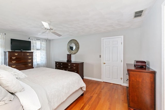 bedroom with baseboards, ceiling fan, light wood-type flooring, and visible vents