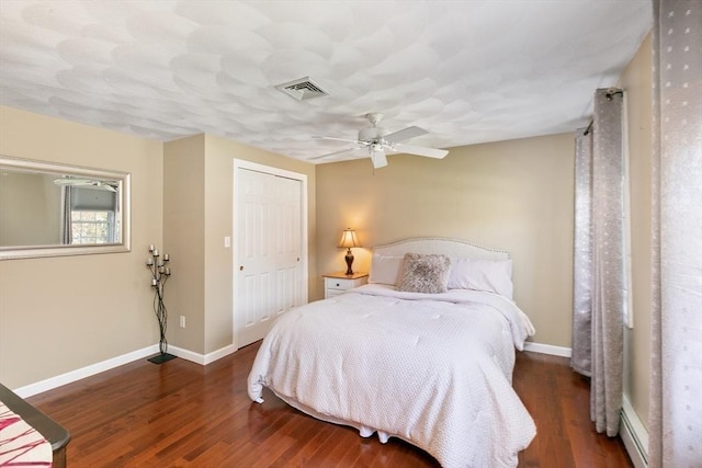 bedroom featuring ceiling fan, visible vents, wood finished floors, baseboards, and a closet