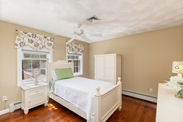 bedroom with visible vents, baseboard heating, and dark wood finished floors