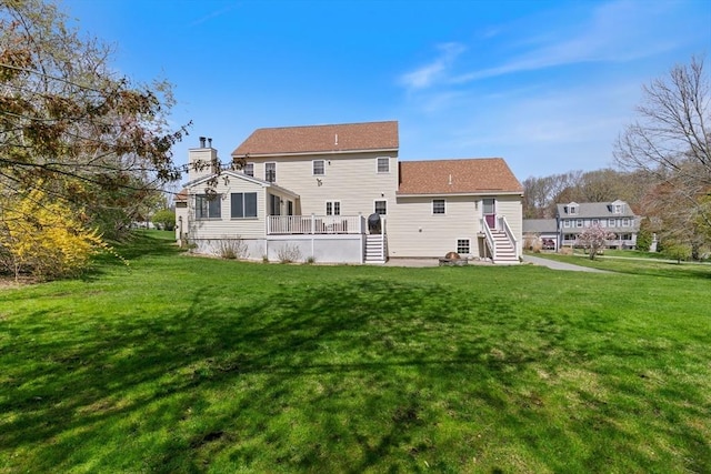 rear view of house with a lawn, a chimney, and a wooden deck