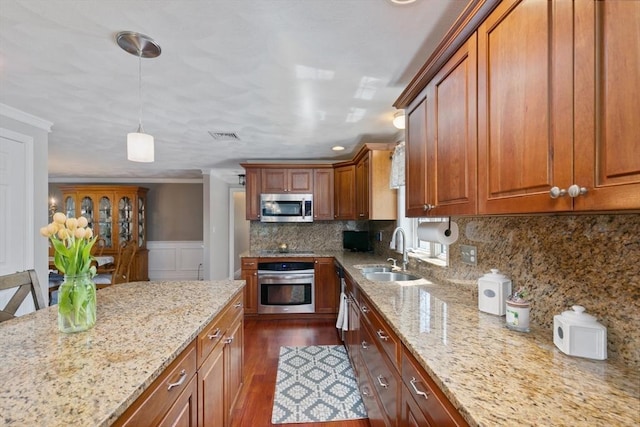 kitchen with brown cabinetry, a sink, appliances with stainless steel finishes, and dark wood-type flooring