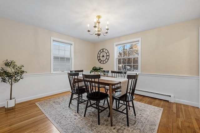 dining room featuring wood-type flooring, a chandelier, and baseboard heating