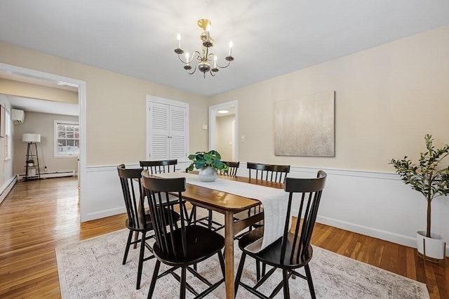 dining area featuring an AC wall unit, an inviting chandelier, and light wood-type flooring