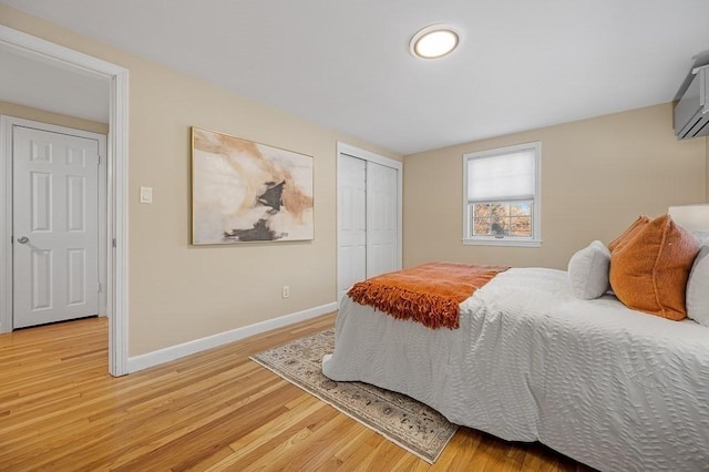 bedroom featuring a wall mounted air conditioner and light hardwood / wood-style flooring