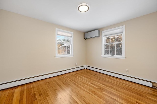 spare room featuring an AC wall unit, a baseboard heating unit, and light hardwood / wood-style flooring