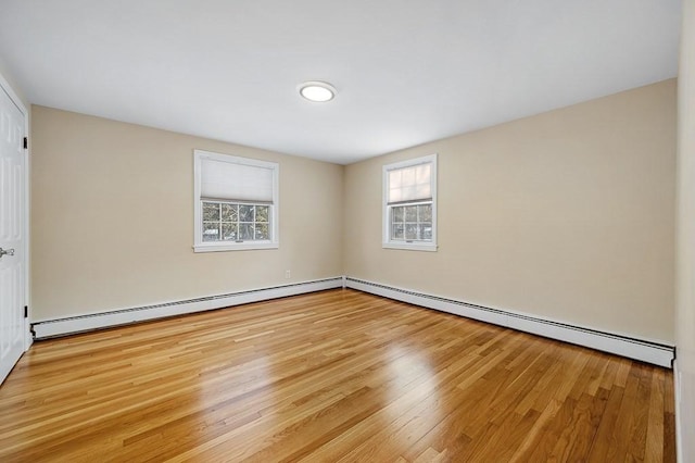 empty room with a baseboard heating unit and light hardwood / wood-style flooring