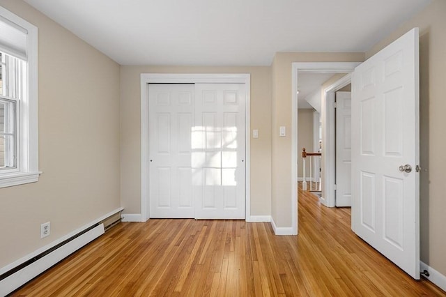 foyer featuring a baseboard radiator, a wealth of natural light, and light hardwood / wood-style flooring