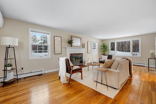 living room featuring a fireplace, baseboard heating, and light hardwood / wood-style flooring