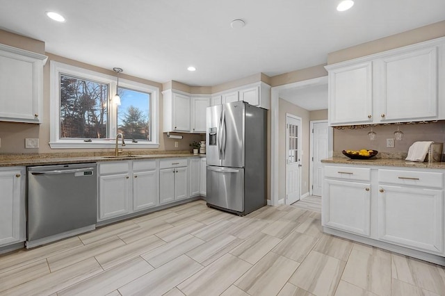 kitchen with sink, hanging light fixtures, white cabinets, and appliances with stainless steel finishes