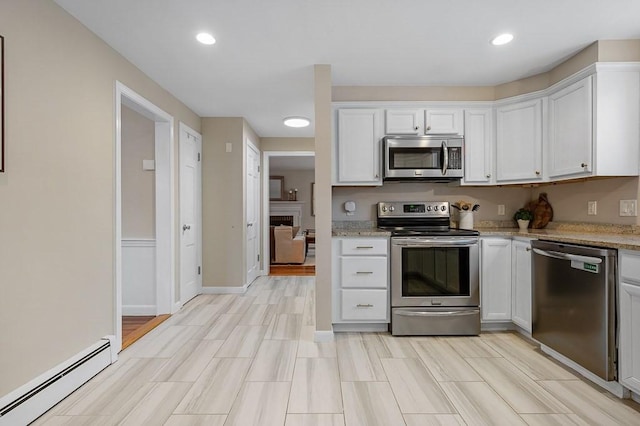 kitchen with a baseboard radiator, stainless steel appliances, light stone countertops, and white cabinets