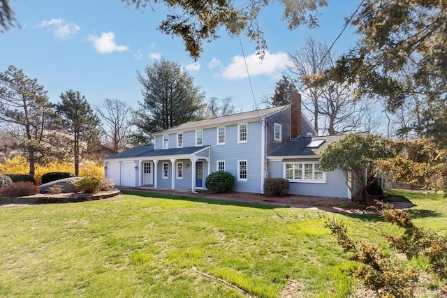 colonial-style house featuring a chimney, a front yard, and a garage