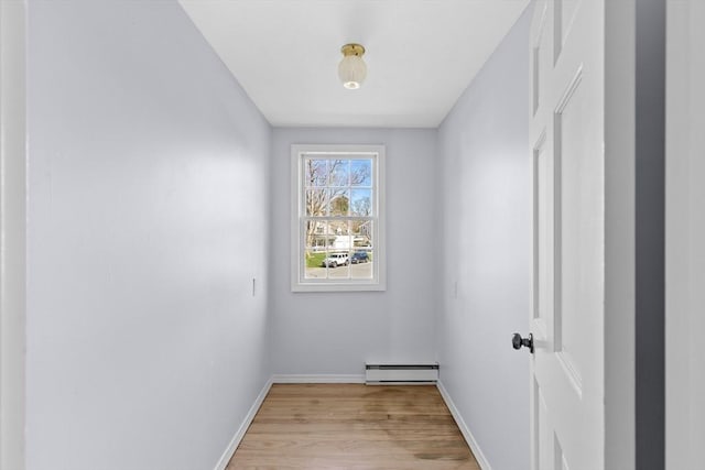 interior space featuring a baseboard heating unit, light wood-style floors, and baseboards