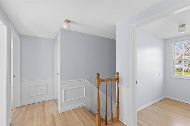 hall featuring a wainscoted wall, wood finished floors, and an upstairs landing