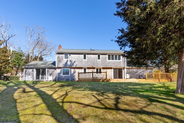 rear view of property with a lawn, a chimney, and a deck