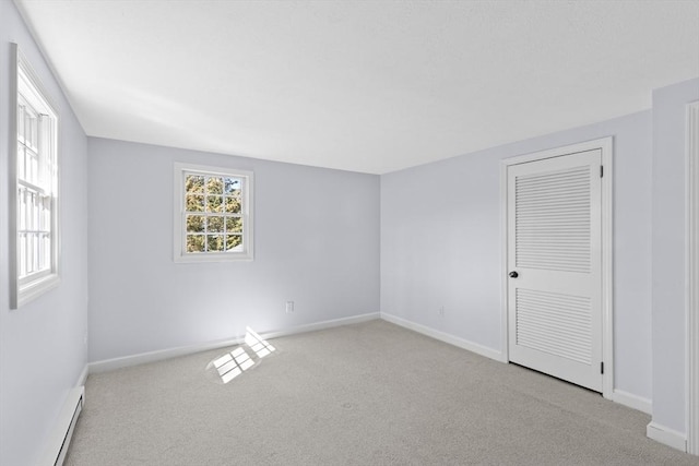 carpeted empty room with a baseboard radiator and baseboards