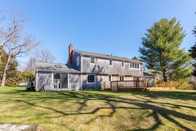 rear view of house featuring a yard, a chimney, fence, and a deck