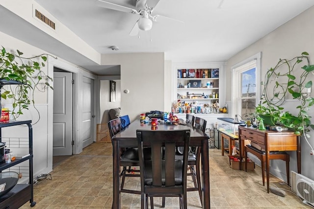 dining space with built in shelves and ceiling fan