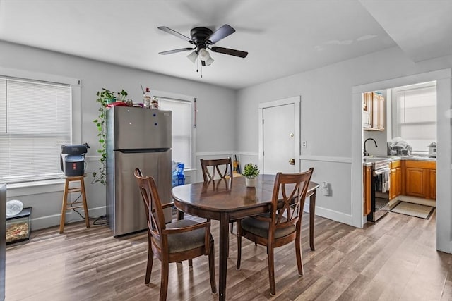 dining room with ceiling fan, sink, and light hardwood / wood-style floors