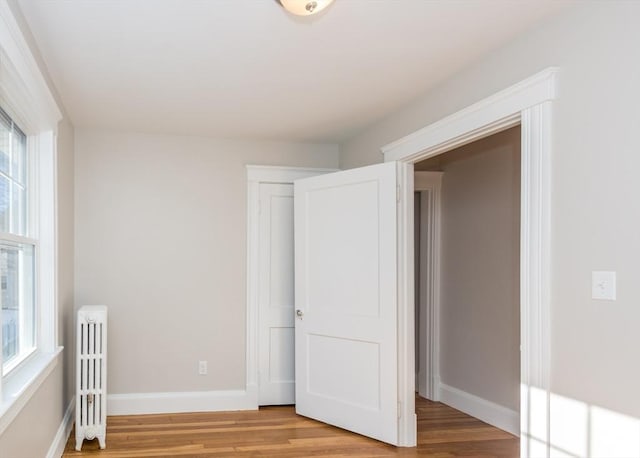 unfurnished bedroom featuring radiator heating unit and light hardwood / wood-style floors