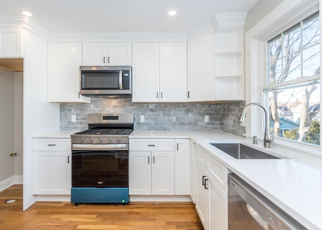 kitchen with stainless steel appliances, sink, and white cabinets