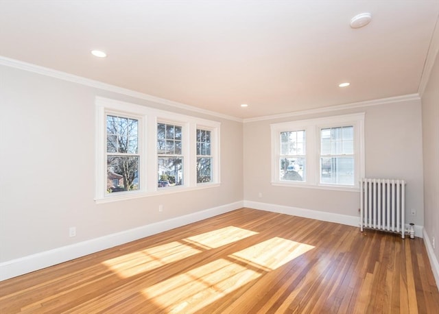 empty room with hardwood / wood-style flooring, ornamental molding, and radiator