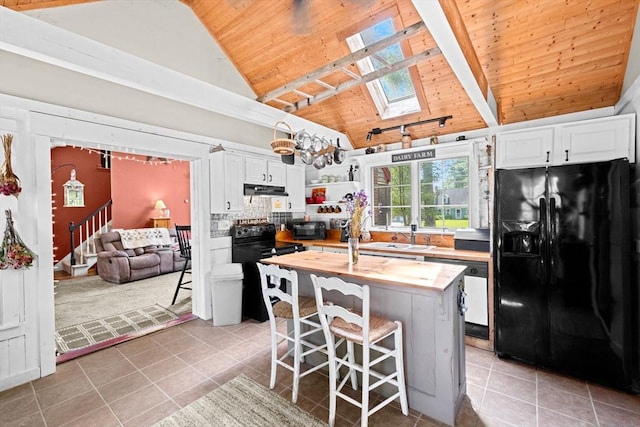18 Russell Holmes Way, Carver, MA 02330 - kitchen featuring black appliances, wood counters, a wooden ceiling with exposed beams, a skylight, and light tile patterned flooring