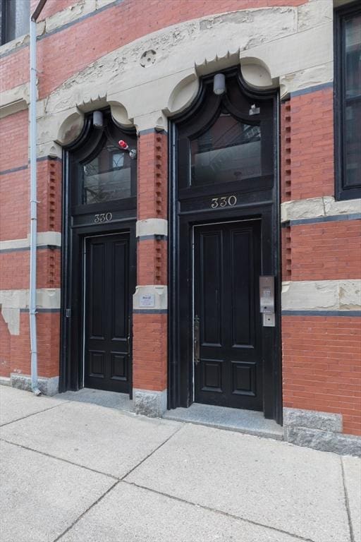 doorway to property featuring brick siding