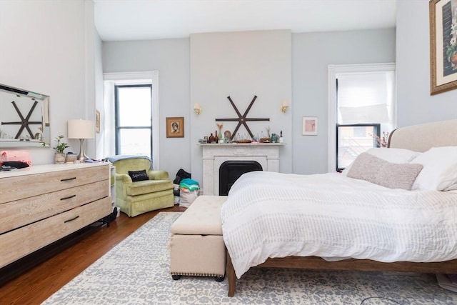 bedroom with dark wood-style floors and a fireplace