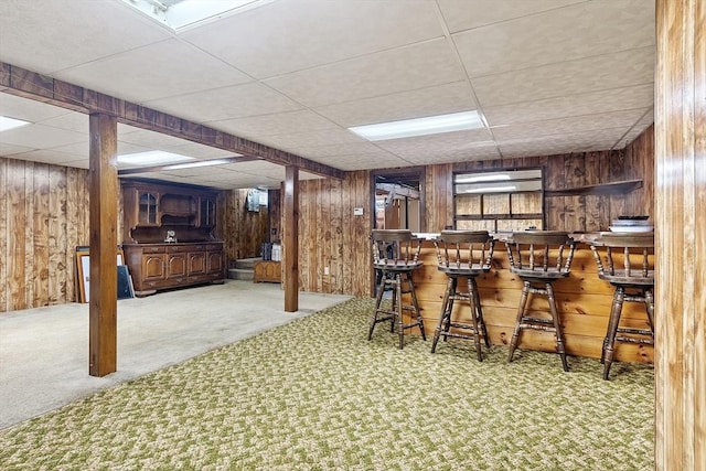 bar featuring a paneled ceiling, carpet flooring, and wood walls