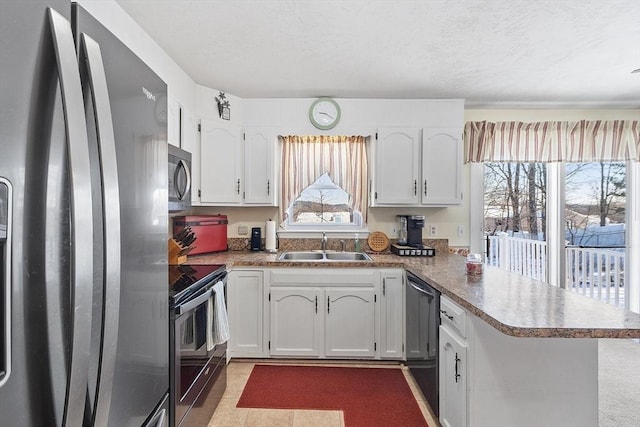 kitchen with light tile patterned flooring, appliances with stainless steel finishes, sink, white cabinets, and kitchen peninsula