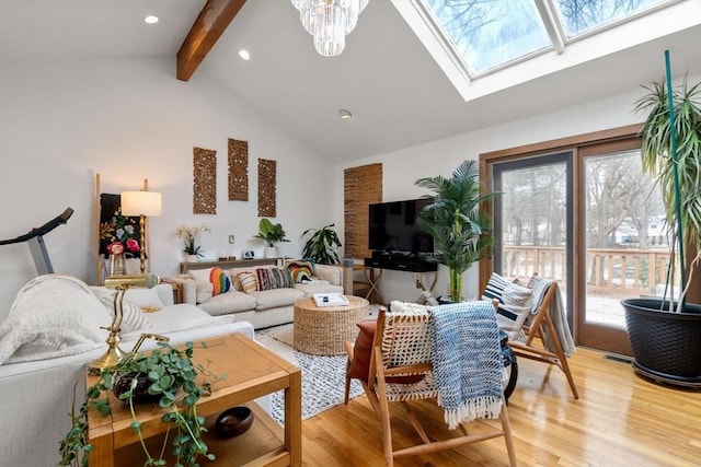 living room featuring vaulted ceiling with skylight, an inviting chandelier, and light wood-type flooring