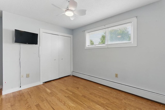 1064 James St Unit 1064, Chicopee, MA 01022 - unfurnished bedroom featuring a baseboard radiator, light wood-style floors, a closet, ceiling fan, and a textured ceiling