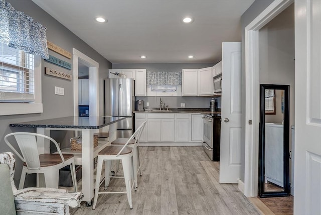 kitchen with sink, stainless steel appliances, light hardwood / wood-style floors, and white cabinets