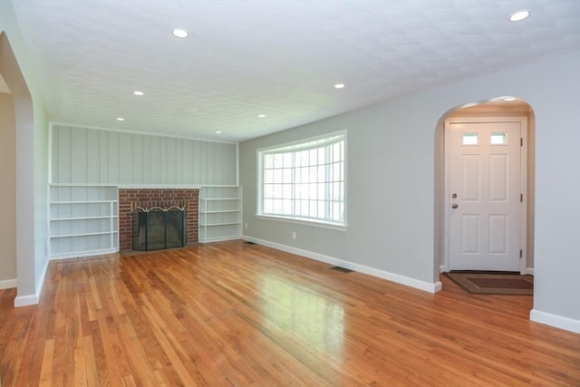 80 Dobbins St, Waltham, MA 02451 - unfurnished living room featuring arched walkways, baseboards, built in shelves, recessed lighting, and light wood-style floors