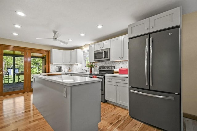 11 Fern Ave, Amesbury, MA 01913 - kitchen featuring appliances with stainless steel finishes, a kitchen island, backsplash, light wood-style floors, and light countertops