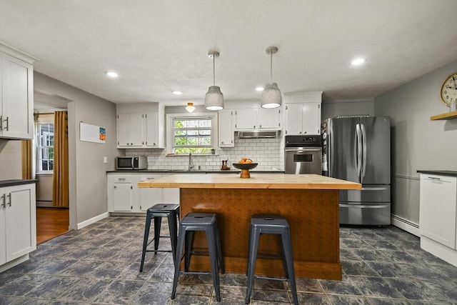 11 Fern Ave, Amesbury, MA 01913 - kitchen featuring stainless steel appliances, wooden counters, under cabinet range hood, white cabinets, and decorative backsplash