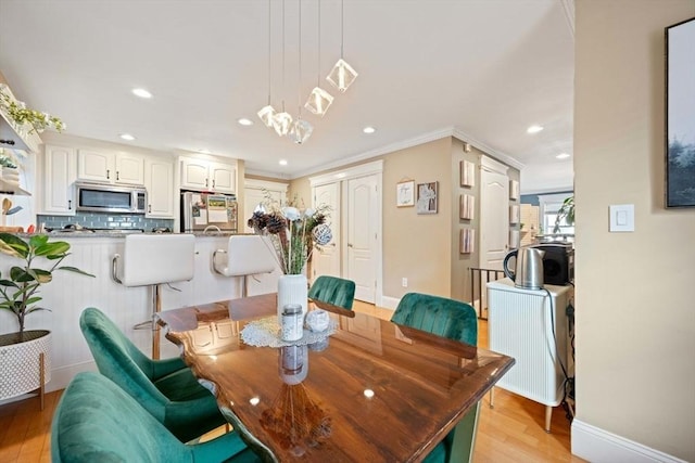 dining space with crown molding, light wood finished floors, recessed lighting, and baseboards