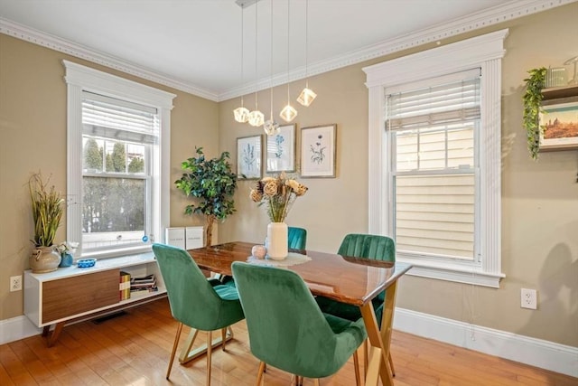 dining room featuring ornamental molding, a notable chandelier, light wood-style flooring, and baseboards