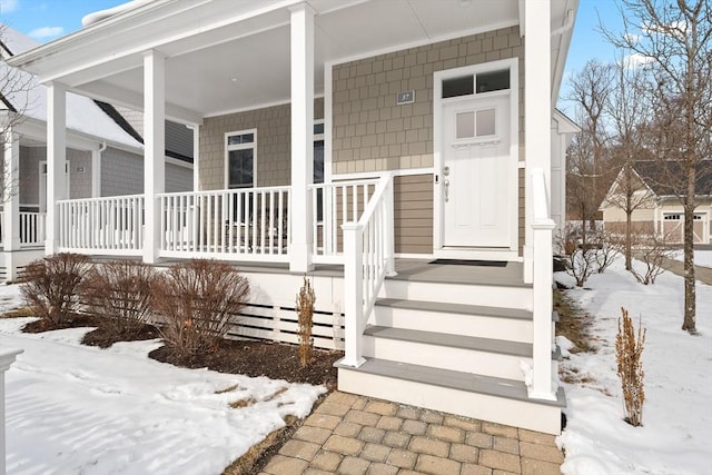 snow covered property entrance with covered porch