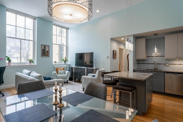 living area with a towering ceiling, light wood-style floors, plenty of natural light, and recessed lighting
