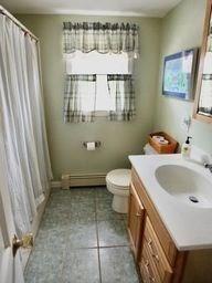 bathroom featuring a baseboard radiator, a wealth of natural light, vanity, and toilet