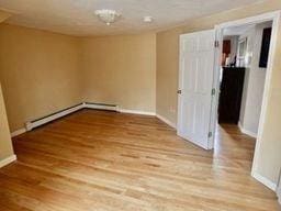 spare room featuring a baseboard heating unit and wood-type flooring