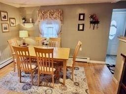 dining space with wood-type flooring and a baseboard radiator