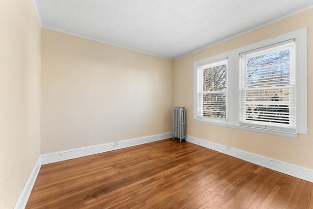 unfurnished room featuring hardwood / wood-style floors, radiator heating unit, and baseboards