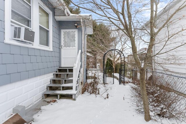 snow covered property entrance featuring cooling unit, fence, and a garage