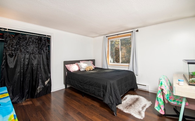 bedroom featuring a textured ceiling, baseboard heating, and dark wood-type flooring